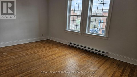 A room with wooden floors and a window showing a view of a building.