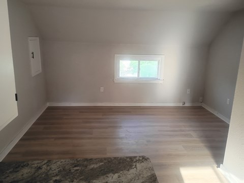 A room with a window and wooden floors.