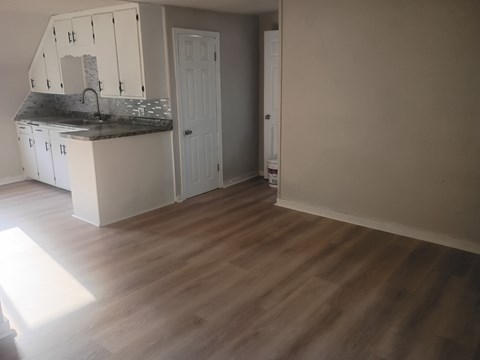 A kitchen with a countertop and cabinets is shown in a room with wooden flooring.
