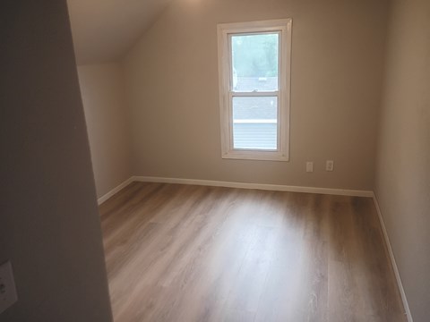 A room with a window and wooden flooring.