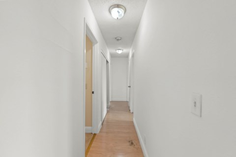 A long hallway with white walls and wood floors.