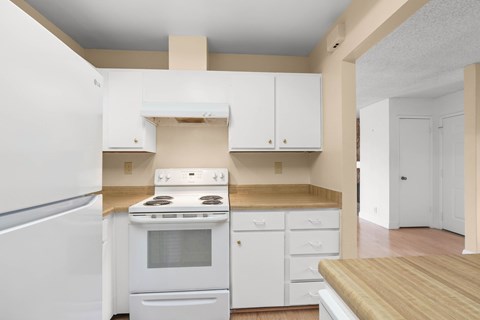 A kitchen with white appliances and cabinets.