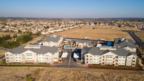 A large white building with a blue roof is surrounded by other buildings and houses.