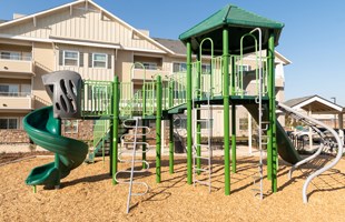 A playground with a green slide and tower.