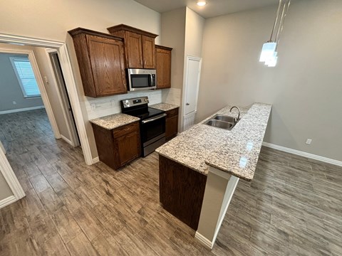 A kitchen with a granite countertop and wooden cabinets.
