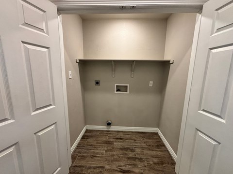 A small, empty room with a brown floor and white walls.