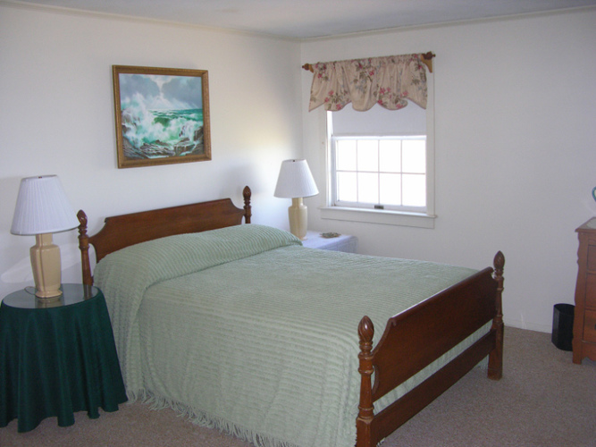 A bedroom with two beds, a nightstand, and a painting on the wall.