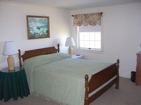 A bedroom with two beds, a nightstand, and a painting on the wall.