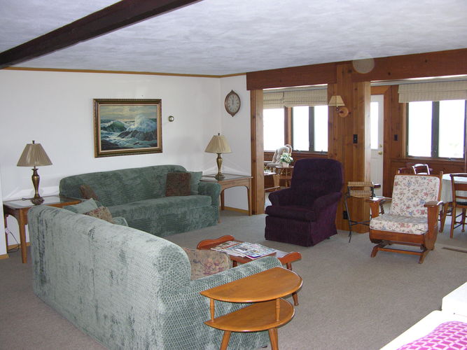 A living room with a green couch, a purple chair, and a painting on the wall.