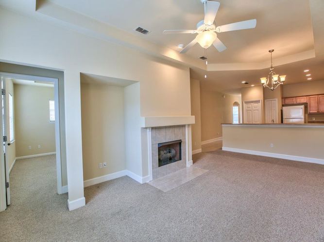 A spacious living room with a fireplace and a ceiling fan.