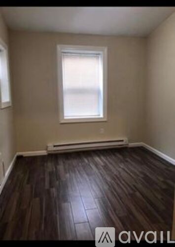 A room with a window and wooden flooring.