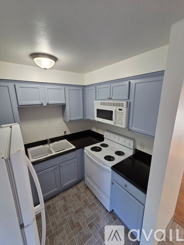 A kitchen with a white refrigerator and a white microwave above the stove.