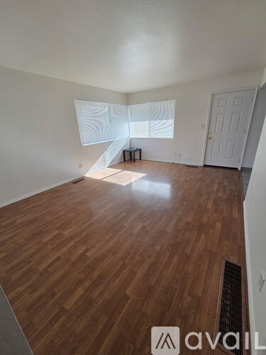 A room with wooden flooring and a window with blinds.