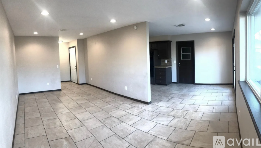 A spacious room with tiled flooring and a large window on the right side.