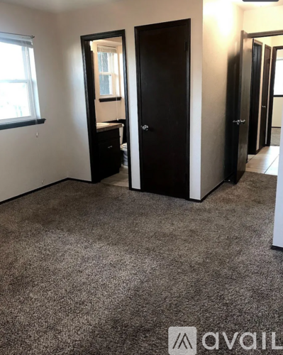 A room with a carpeted floor, a large mirror, and a door.