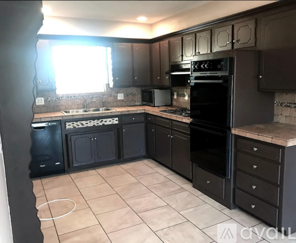 A kitchen with black cabinets and appliances.