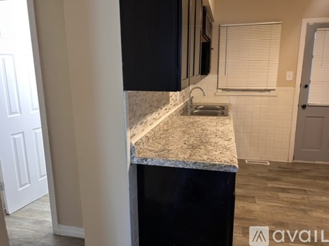 A kitchen with black cabinets and a granite countertop.