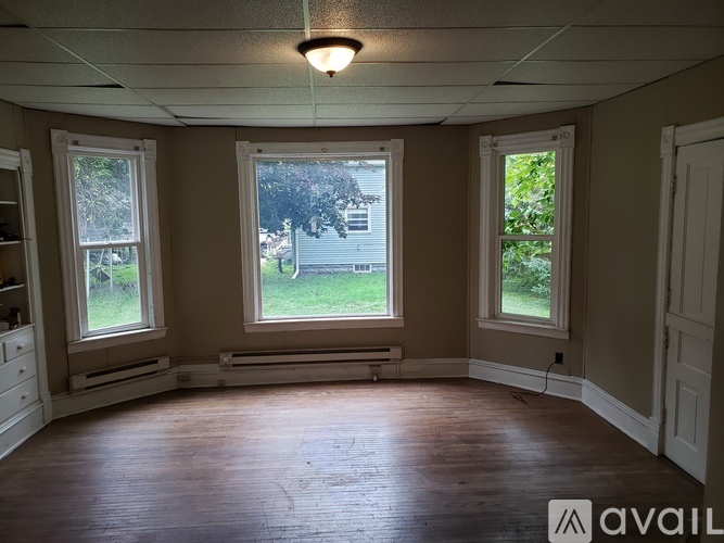 A room with wooden floors and three windows.