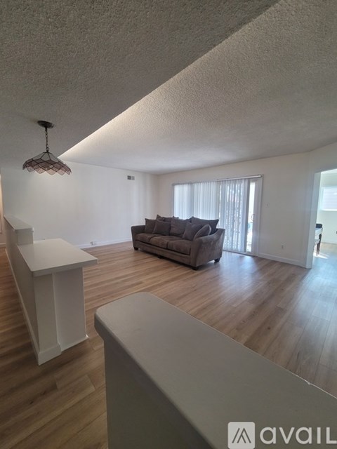 A living room with a couch and a hanging light fixture.