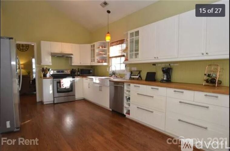 A kitchen with white cabinets and a refrigerator is for rent.