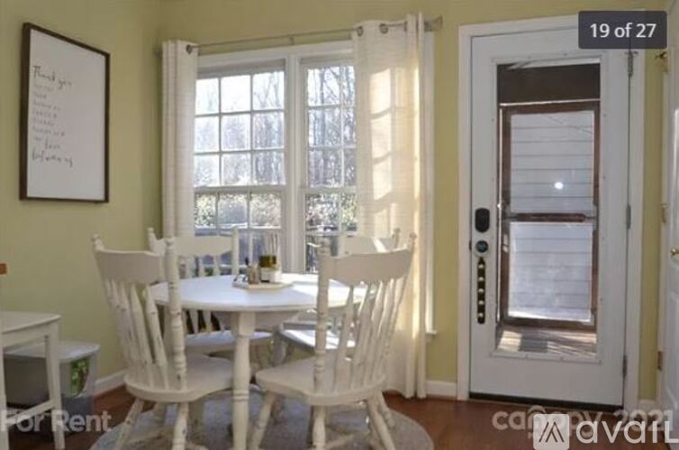 A dining room with a white table and chairs.