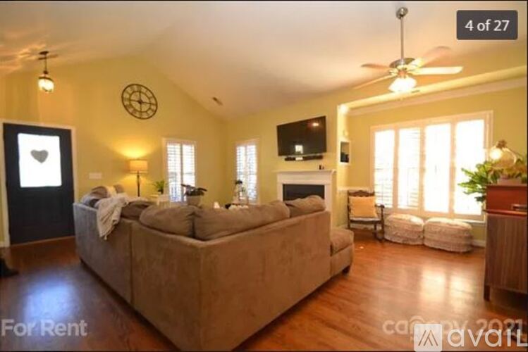 A living room with a couch, a television, and a ceiling fan.