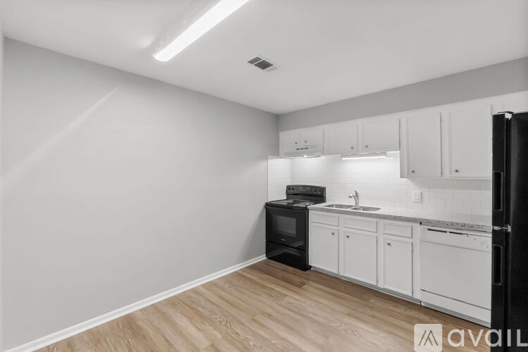 A kitchen with white cabinets and a black refrigerator.