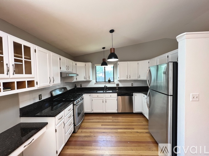 A kitchen with white cabinets and black countertops.
