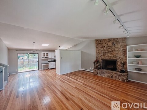 A living room with a stone fireplace and wooden floors.