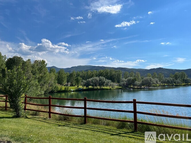 A serene landscape with a lake, trees, and mountains in the distance.