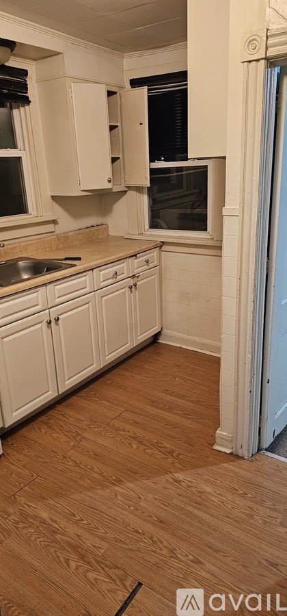 A kitchen with white cabinets and a wooden floor.
