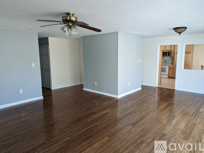 A spacious room with wood flooring and a ceiling fan.