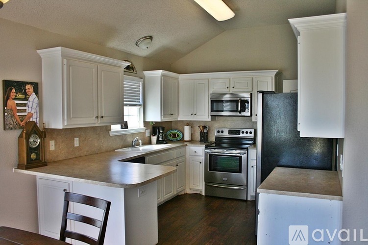 A kitchen with white cabinets and a wooden floor.
