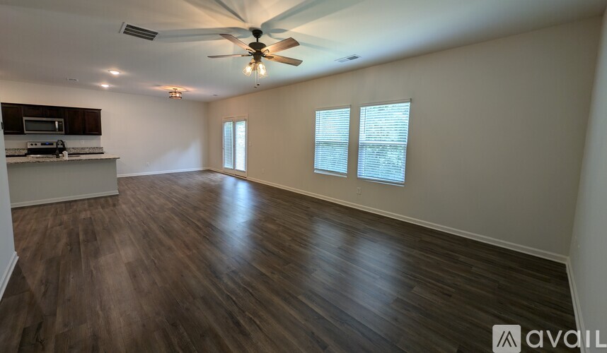 A spacious room with wood flooring and a ceiling fan.