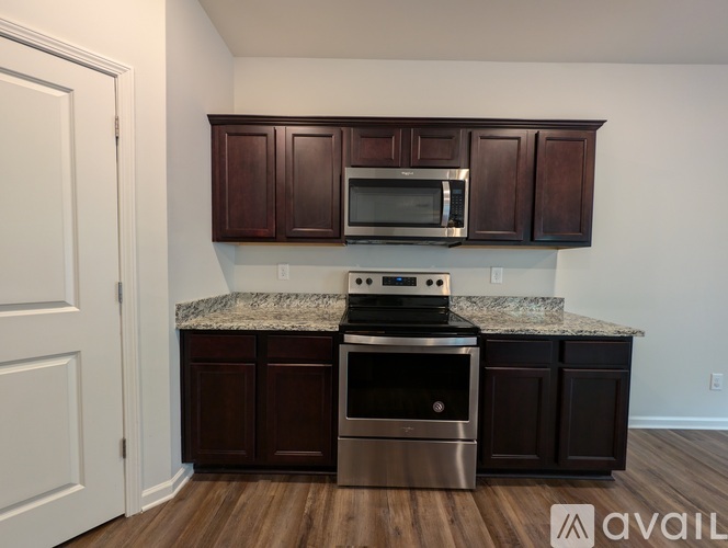 A kitchen with dark brown cabinets and a granite countertop.