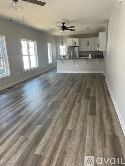 A spacious room with wooden flooring and a ceiling fan.