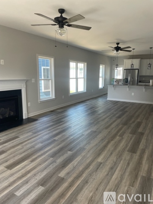 A spacious room with wooden flooring and a fireplace.
