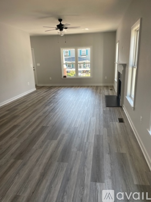 A spacious room with a ceiling fan and a large window.