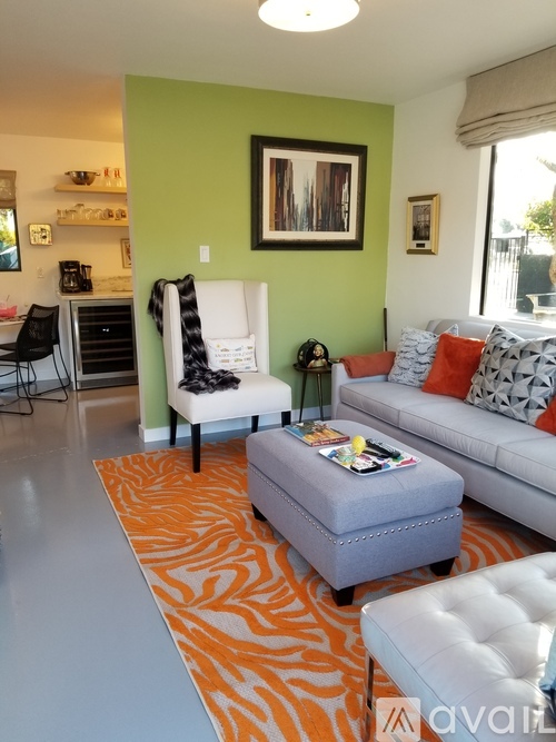 A living room with a white couch and a grey ottoman.
