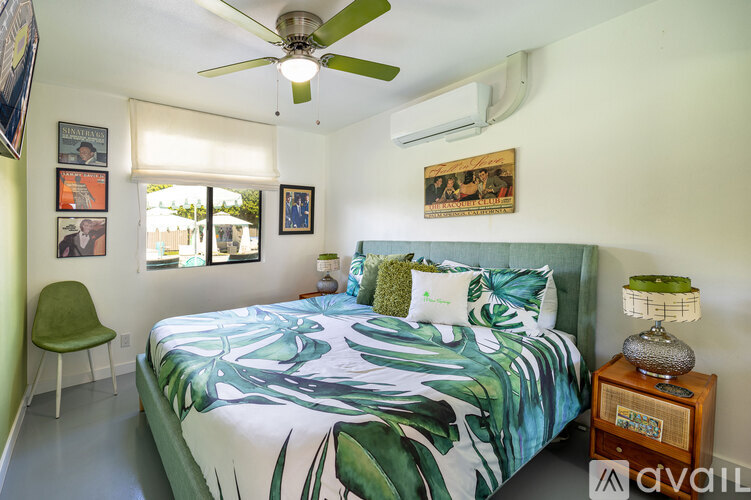 A bedroom with a bed, a chair, a ceiling fan, and pictures on the wall.