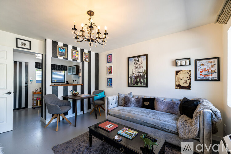 A living room with a grey couch and a chandelier.