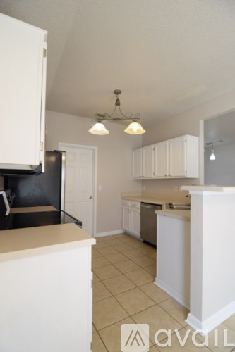 A kitchen with white cabinets and a black fridge.