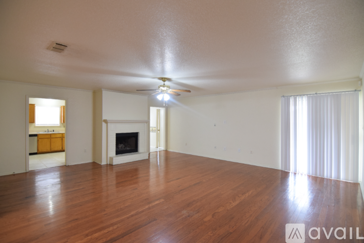 A spacious living room with a fireplace and wooden floors.