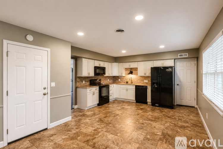 A kitchen with tile flooring and a black refrigerator.