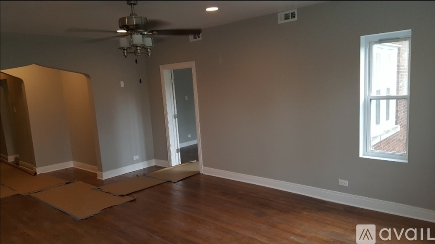 A room with a ceiling fan and a window with a view of a brick building outside.