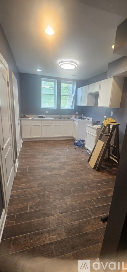A kitchen with wooden floors and white cabinets.