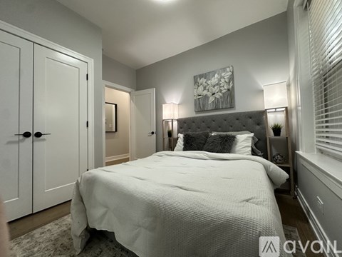 A bedroom with a large bed and a painting on the wall.