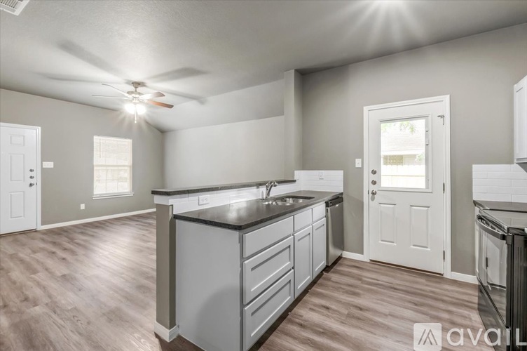 A kitchen with a black countertop and white cabinets.