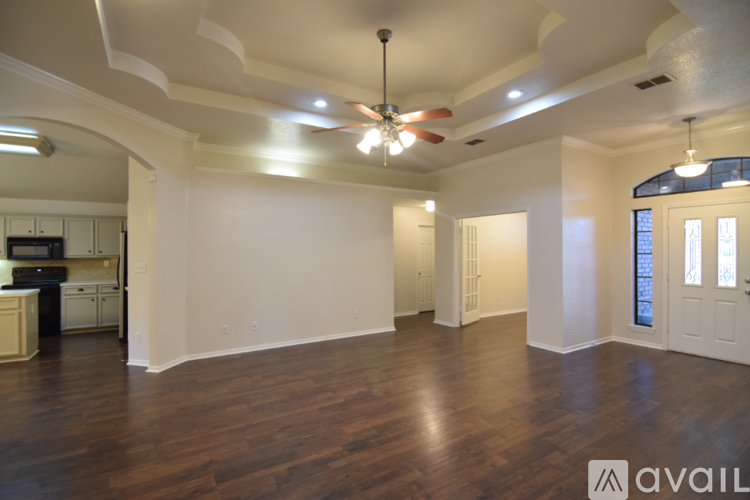 A spacious room with a ceiling fan and wooden flooring.