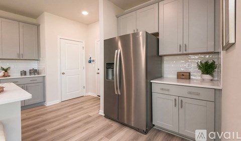 A modern kitchen with a stainless steel refrigerator and white cabinets.